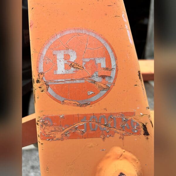 Worn BT decal and 1,000 kg capacity marking on the orange pallet jack fork